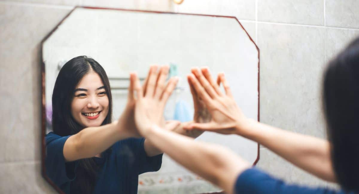 self-love quotes woman looking in mirror and smiling